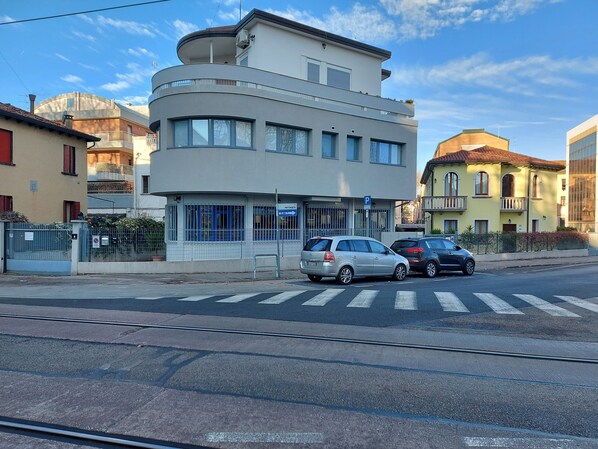 Un edificio moderno con fachada curva, un cartel de estacionamiento y un paso de peatones.