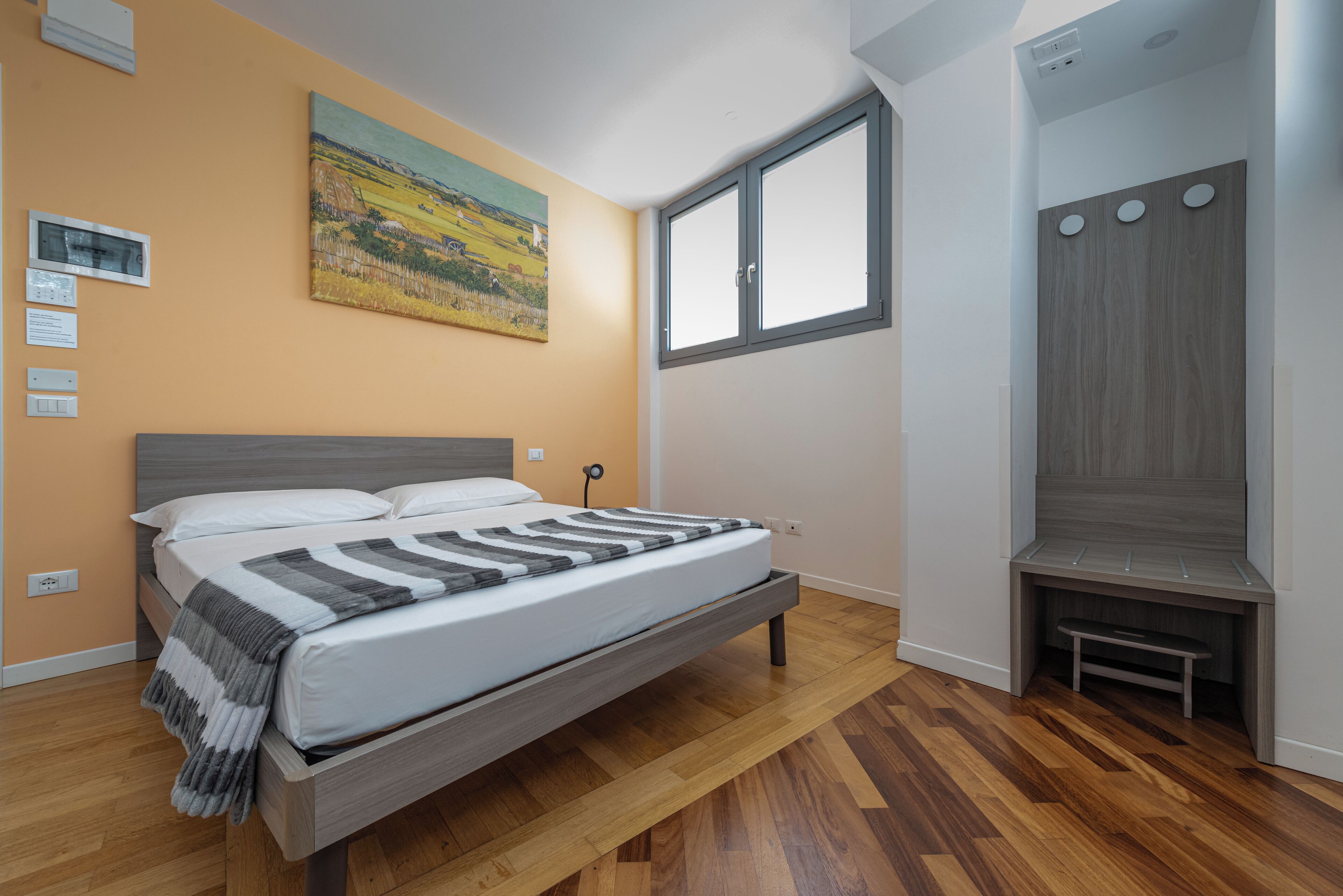 Een slaapkamer met een bed, een schilderij, een raam en een bank.