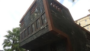 Un bâtiment dont la façade est marquée par les intempéries, doté de grandes fenêtres et d’un balcon avec une balustrade.