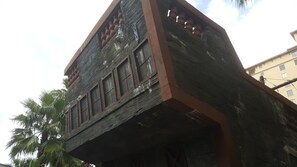 Un edificio con fachada desgastada, ventanas amplias y un balcón con barandilla.