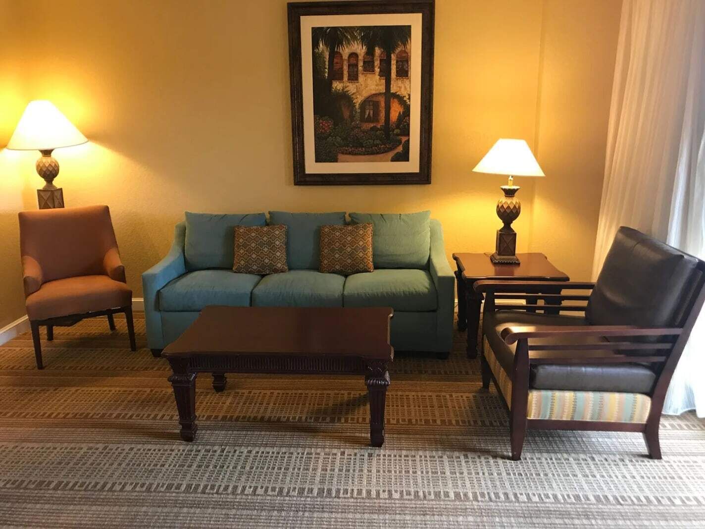 A living room with a sofa, two armchairs, a coffee table, and two lamps.