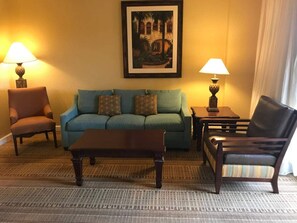 Una sala de estar con un sofá, dos sillones, una mesa de centro y dos lámparas.