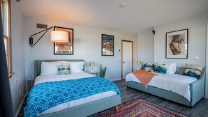 Une chambre d’hôtel moderne avec deux lits, une grande fenêtre et des œuvres d’art accrochées aux murs.