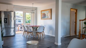A modern kitchen with a stainless steel refrigerator, a dining area with a table and chairs, and a painting on the wall. - Luxury Family Getaway with Designer Touches (Atlantic City)