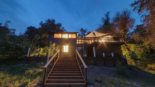 A wooden staircase leading to a building with a balcony, surrounded by trees. - Rivers Breeze - Wine Tastings Included (Healdsburg)