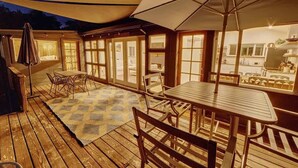 A covered outdoor patio with wooden flooring, a checkered rug, and a table with chairs. - Rivers Breeze - Wine Tastings Included (Healdsburg)