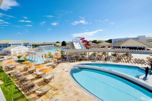 Ett semesterhotell med en stor pool, solstolar, parasoller och en vattenrutschkana.