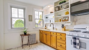A kitchen with white cabinets, a stove, and a window. - Beautiful Providence Apt Near Dtwn & Federal Hill! (Providence)