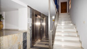 Eine Hotelhalle mit einer Marmor-Rezeption, einer Treppe und einer Reihe von Aufz ügen.