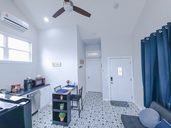 A compact living space with a kitchenette, a dining area, and a seating area with a sofa.