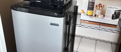 A compact kitchenette with a refrigerator, a microwave, and a coffee maker.