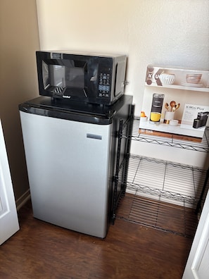 A compact kitchenette with a refrigerator, a microwave, and a coffee maker.