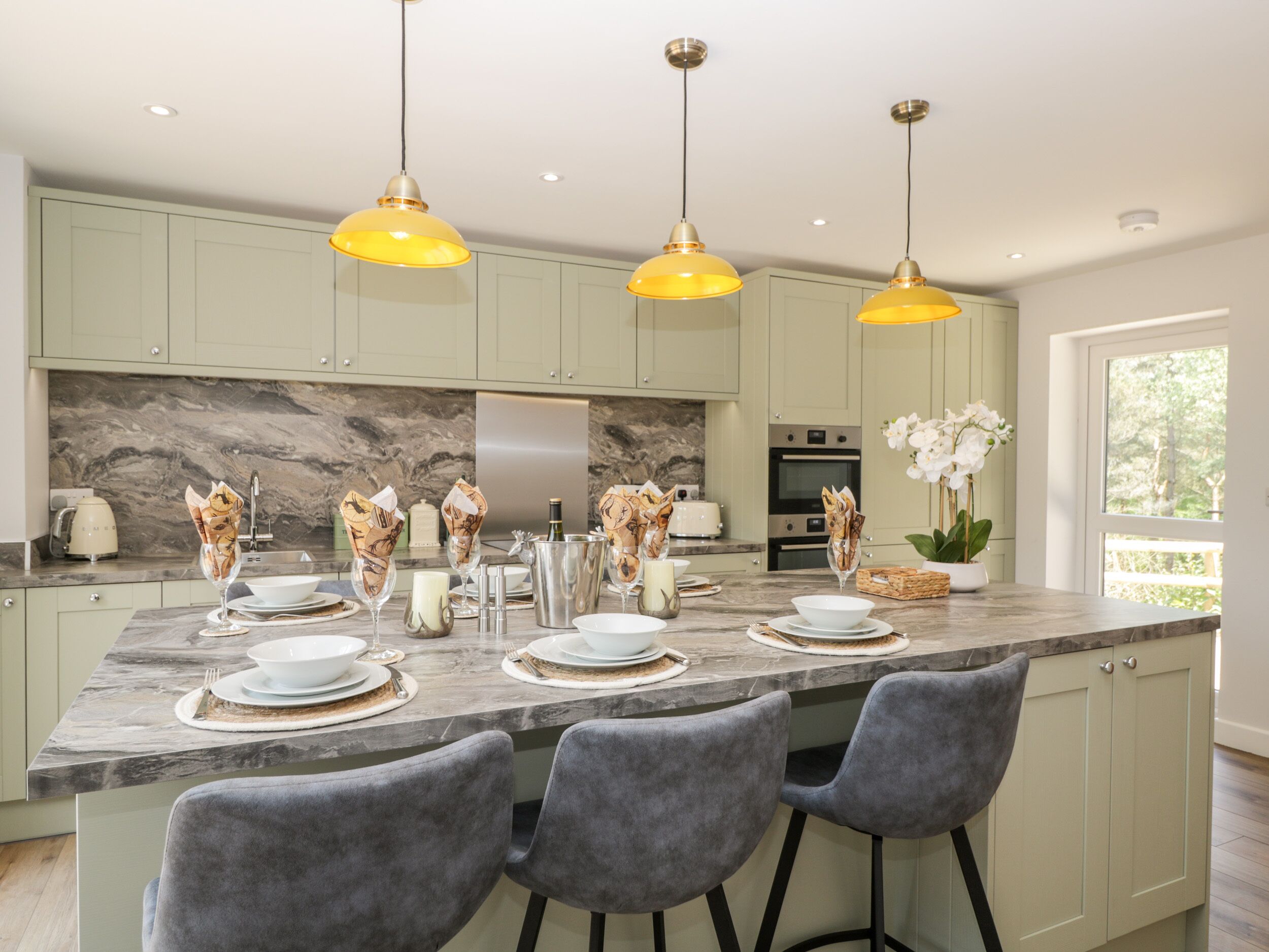 A modern kitchen with a marble countertop, pendant lighting, and a central island with bar stools.