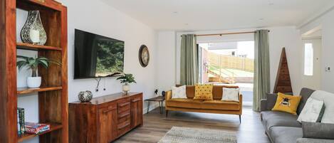 A living room with a wooden cabinet, a sofa, a television, and a view of the outdoors.