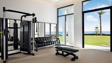 A gym with exercise equipment, a bench, and large windows offering a view of the outdoors.
