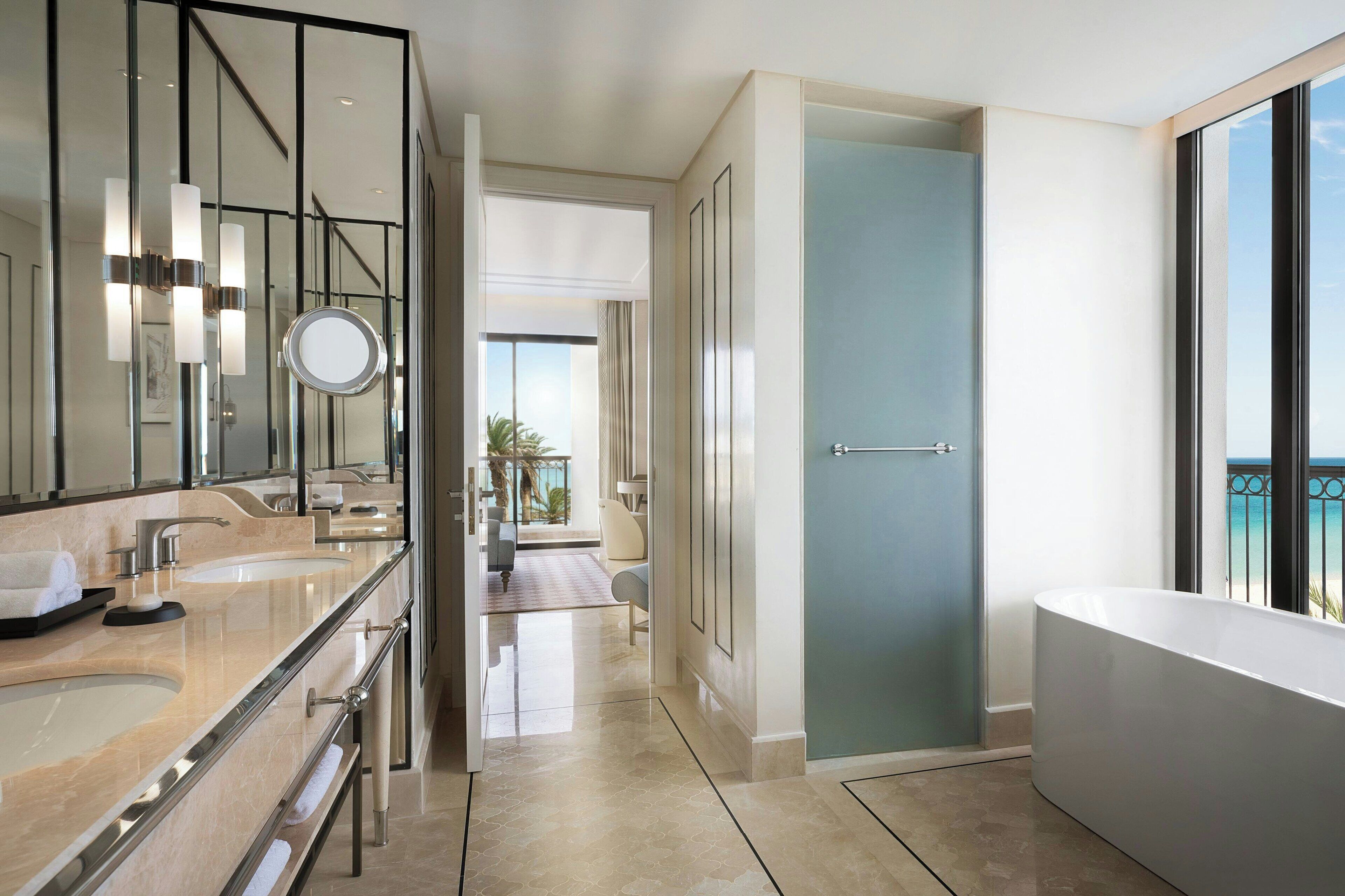 A modern bathroom with a large bathtub, a walk-in shower, and a vanity with a mirror and two sinks.