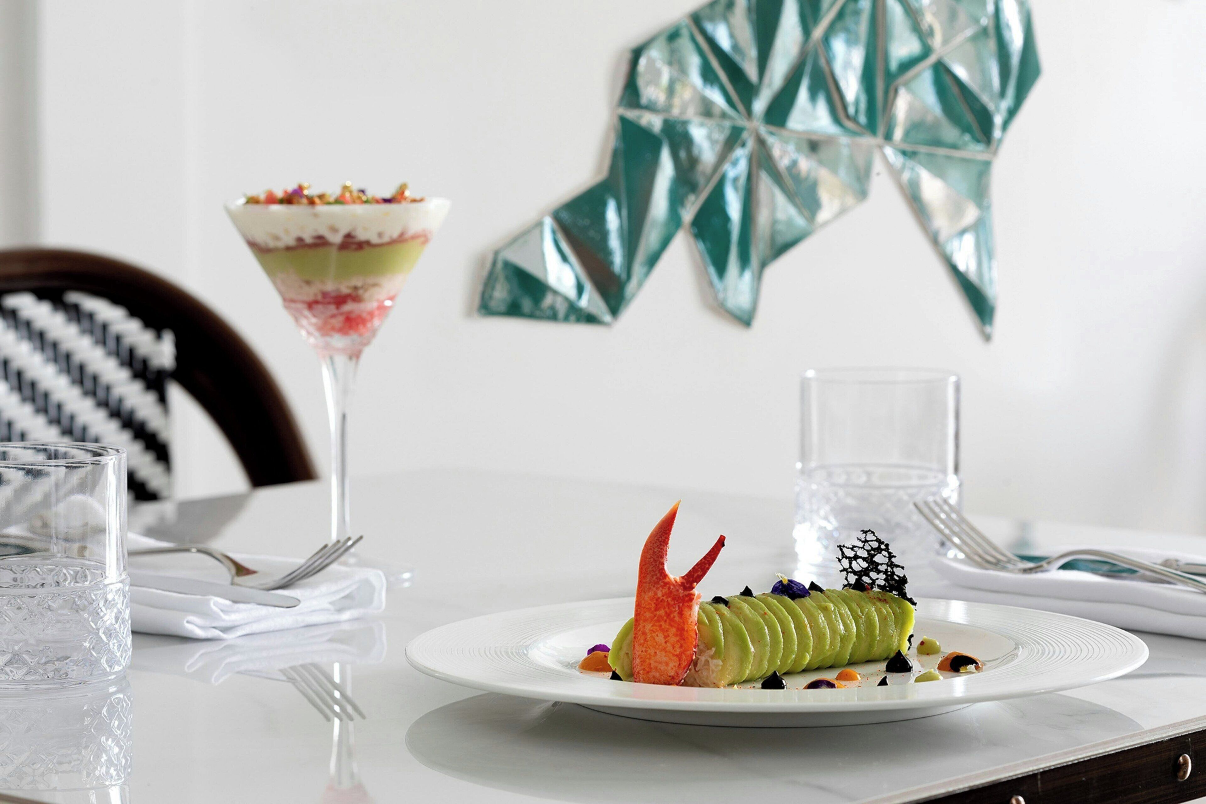 A dining table with a plate of food, a glass of water, and a decorative wall piece.