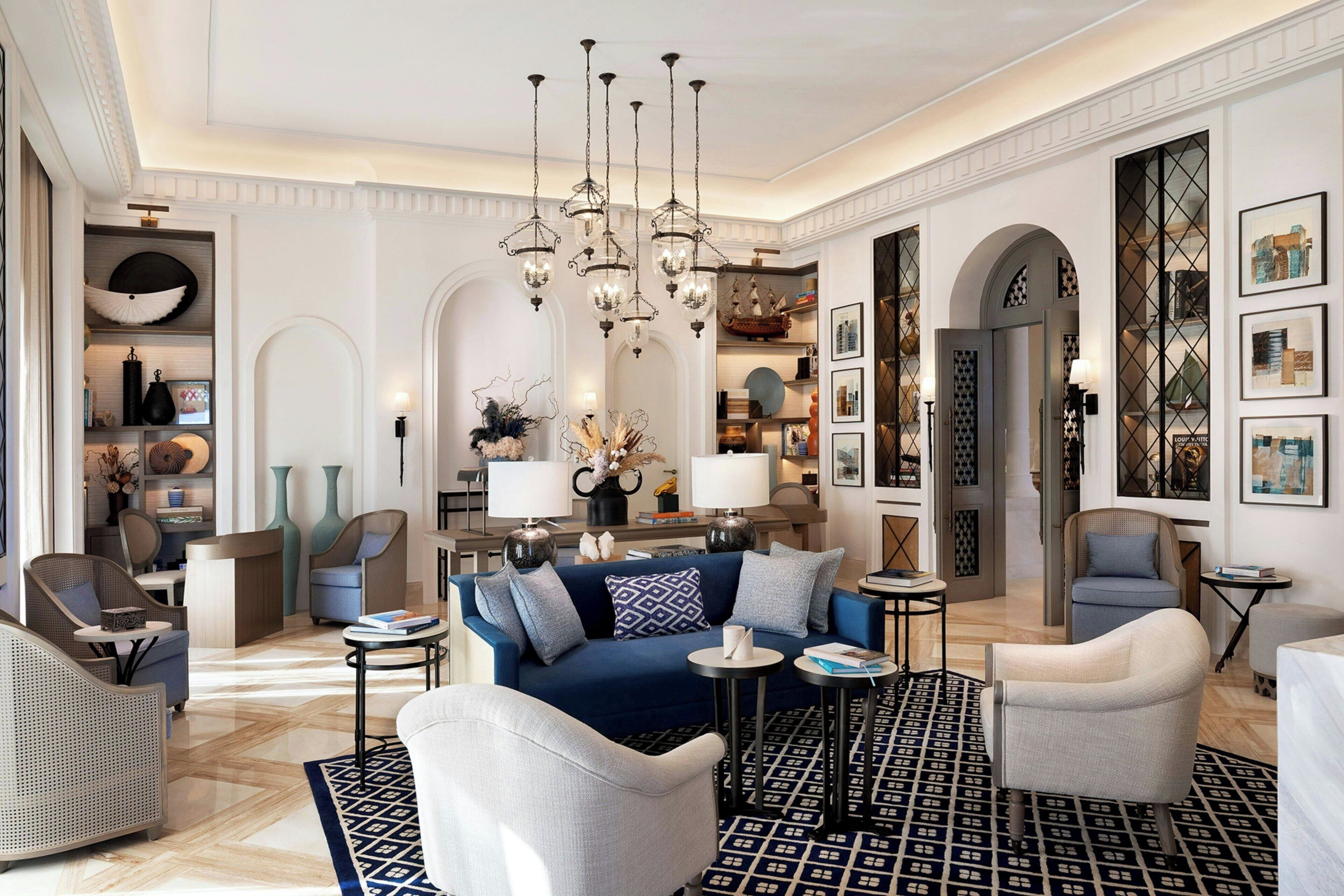 Ein geräumiges Wohnzimmer mit einem blauen Sofa, weißen Sessel und einem gemusterten Teppich.