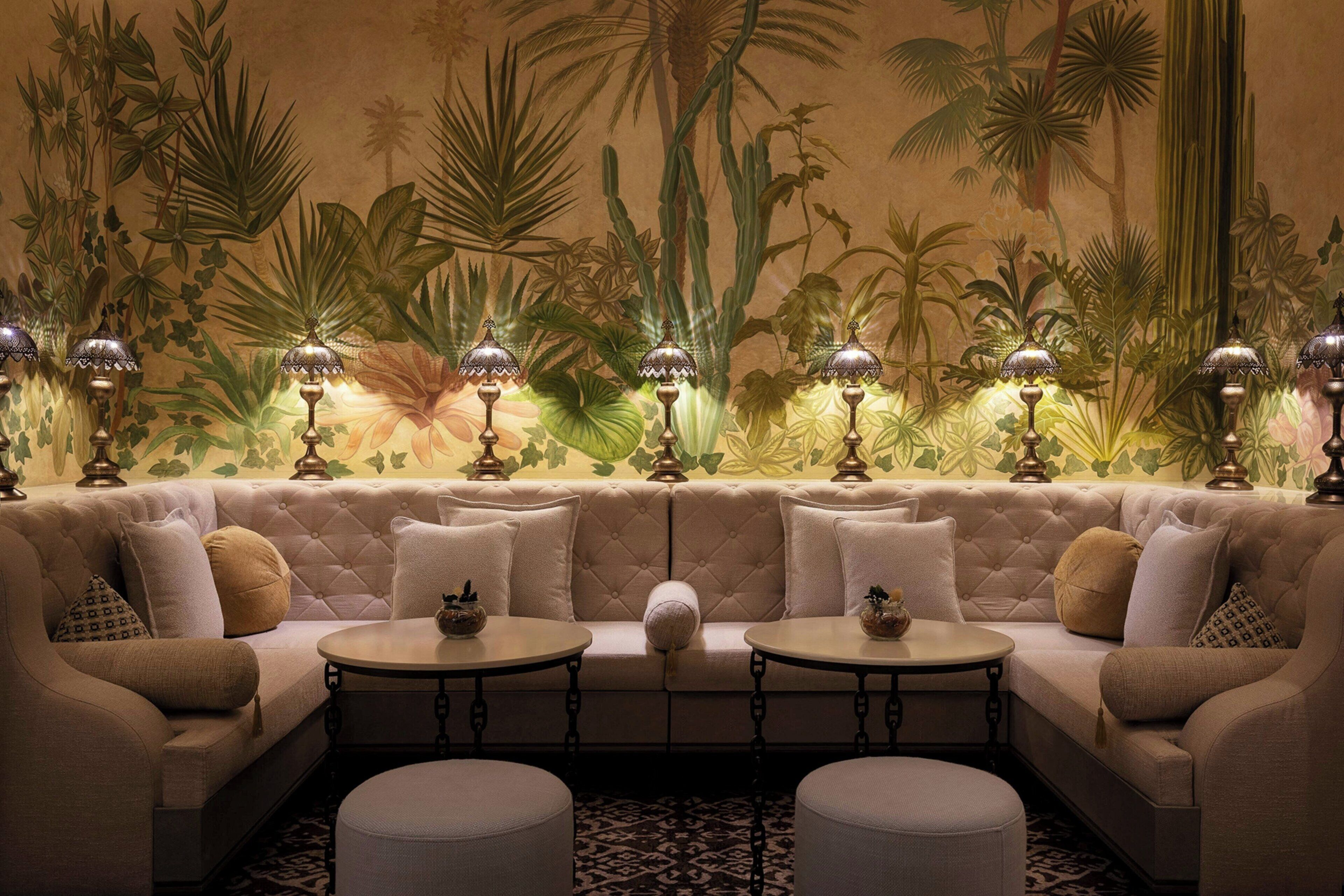 A luxurious lounge area with a sofa, two round tables, and decorative lamps.