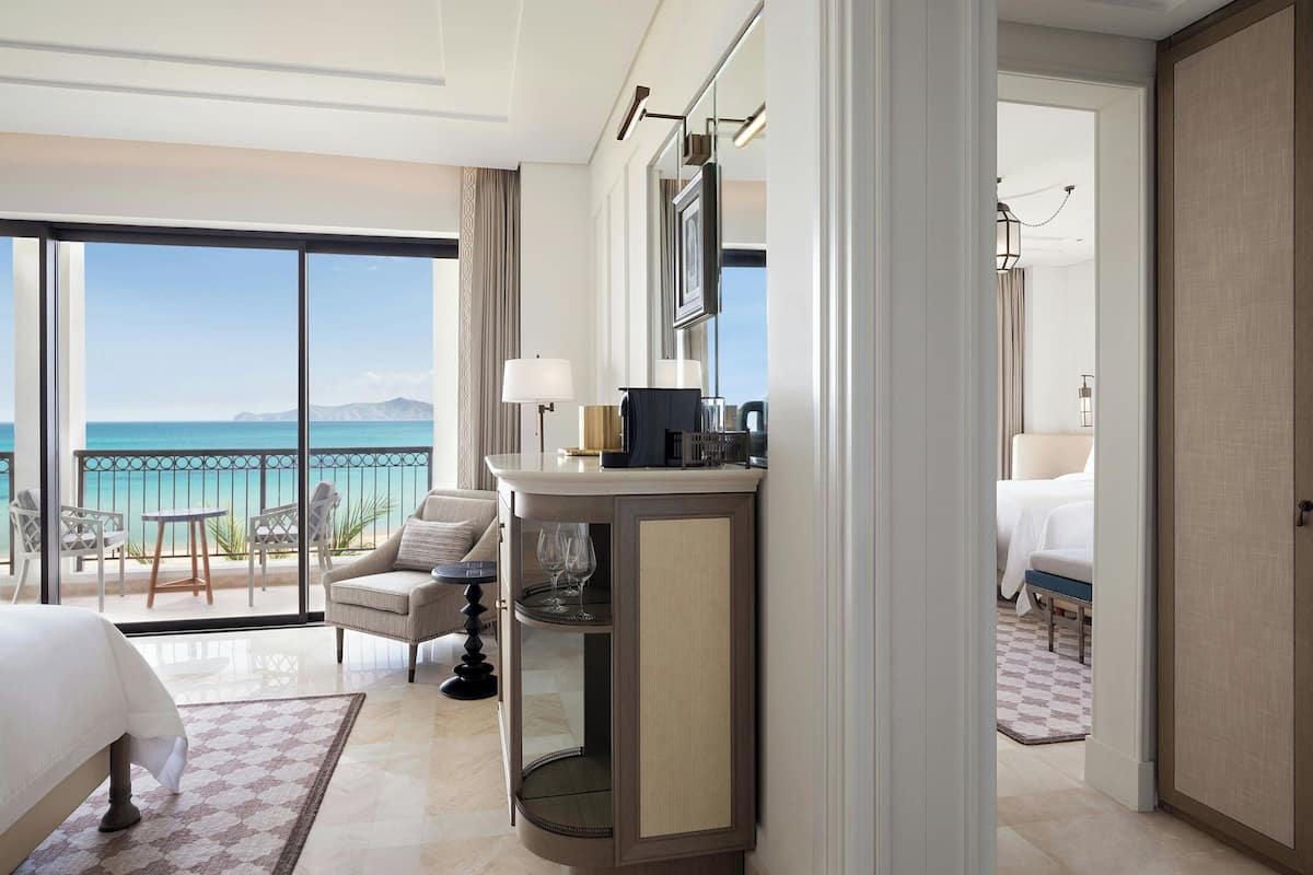 Une chambre d’hôtel dotée d’un grand balcon, d’un lit, d’un bureau et d’une salle de bain.