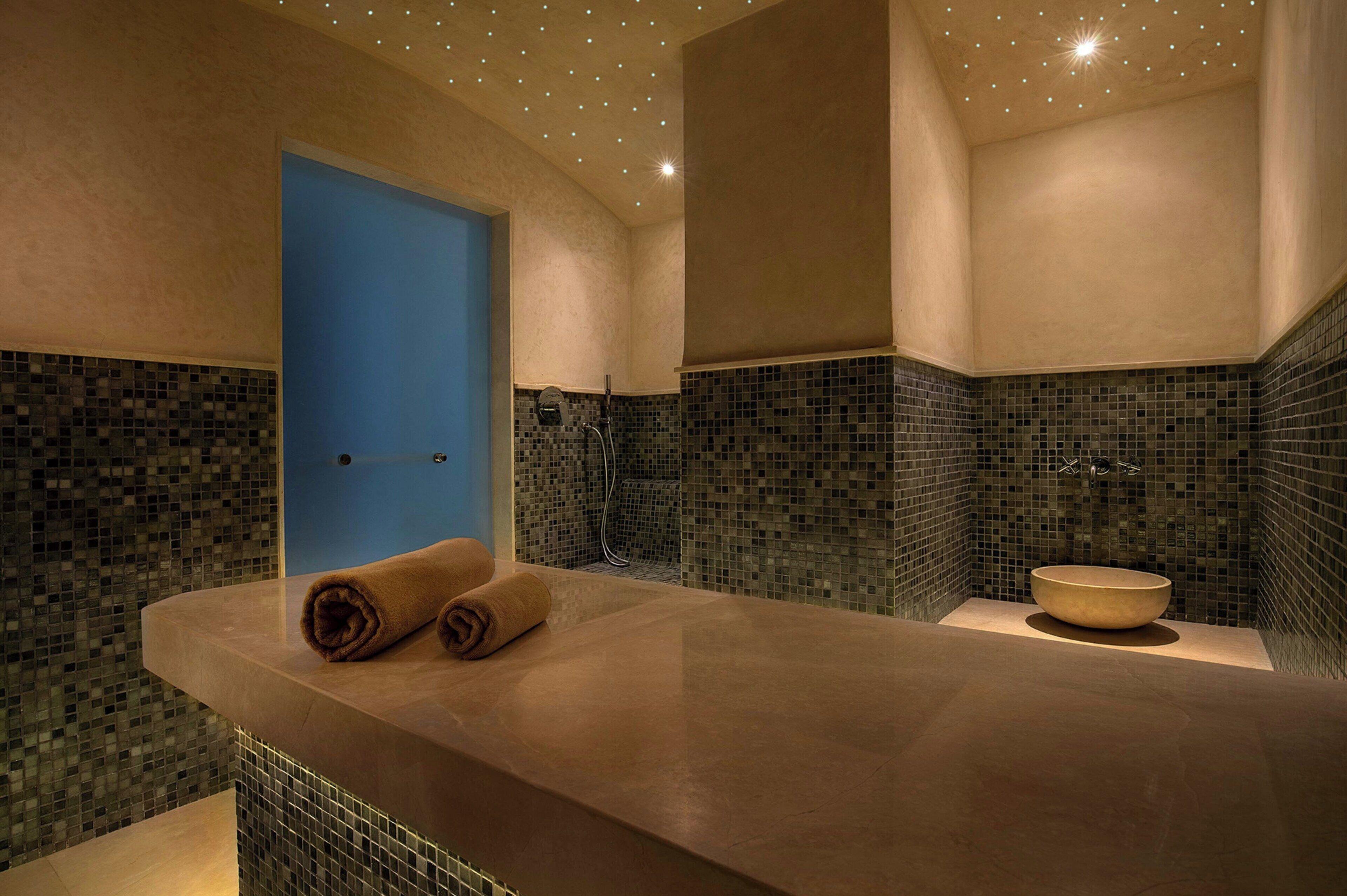 Un baño moderno con una bañera grande, una puerta azul y paredes con mosaicos.