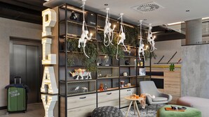 Eine moderne Hotelhalle mit einem großen, beleuchteten 'DAY'-Schild, einer Sitzecke mit rundem Tisch und Hocker, und einem grünen Koffer mit dem Aufdruck 'URBAN JUNGLE' in der Ecke.