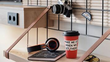 A modern kitchen with wooden cabinetry, a hanging camera, a red coffee cup with motivational text, and a pair of sunglasses on the counter.