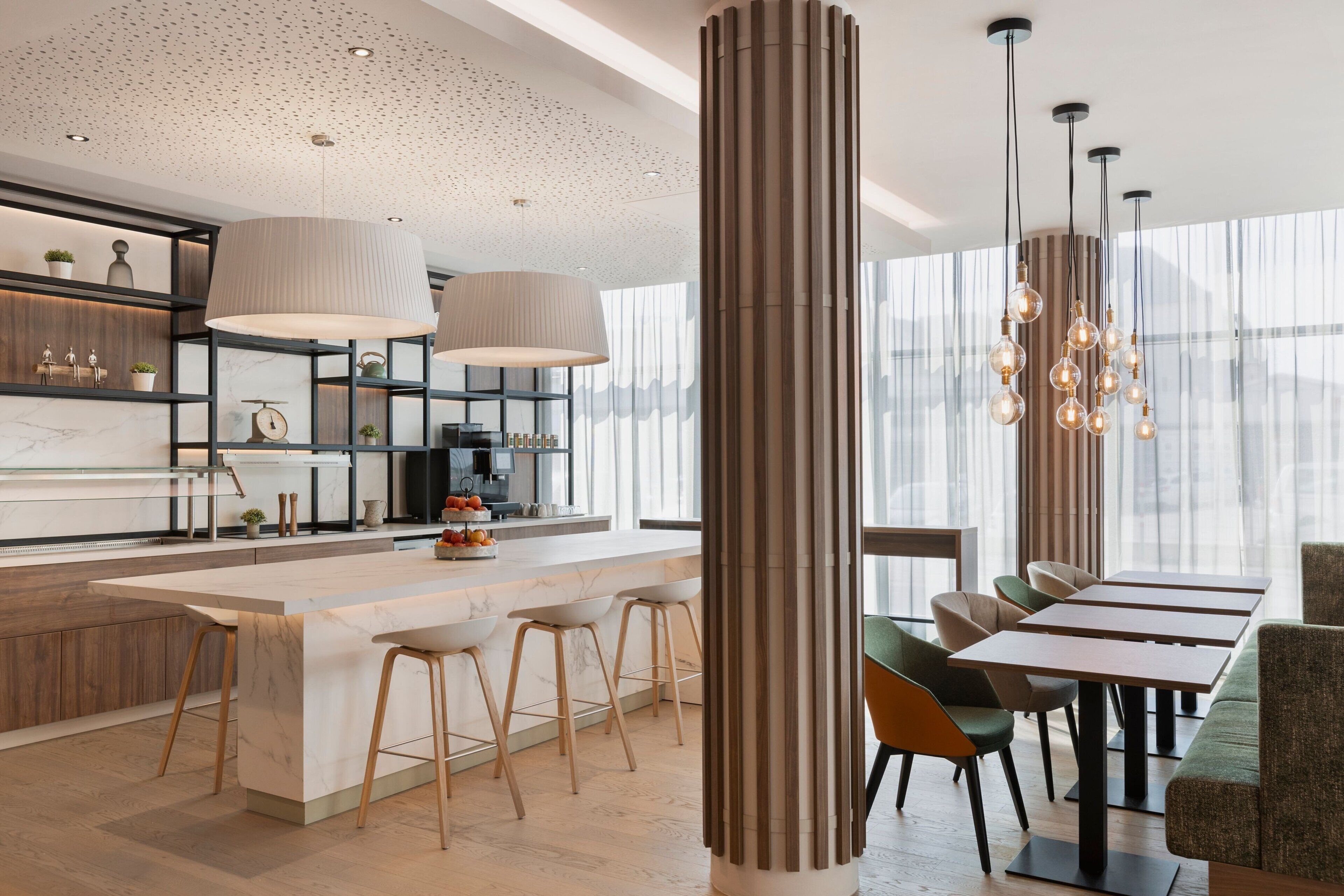A modern kitchen with a large island, bar stools, and pendant lighting.