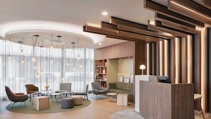 Un hall d’entrée moderne avec un espace salon central, des éléments décoratifs en bois et un comptoir d’accueil.