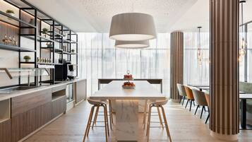A modern kitchen with a marble island, wooden cabinets, and a large pendant light.