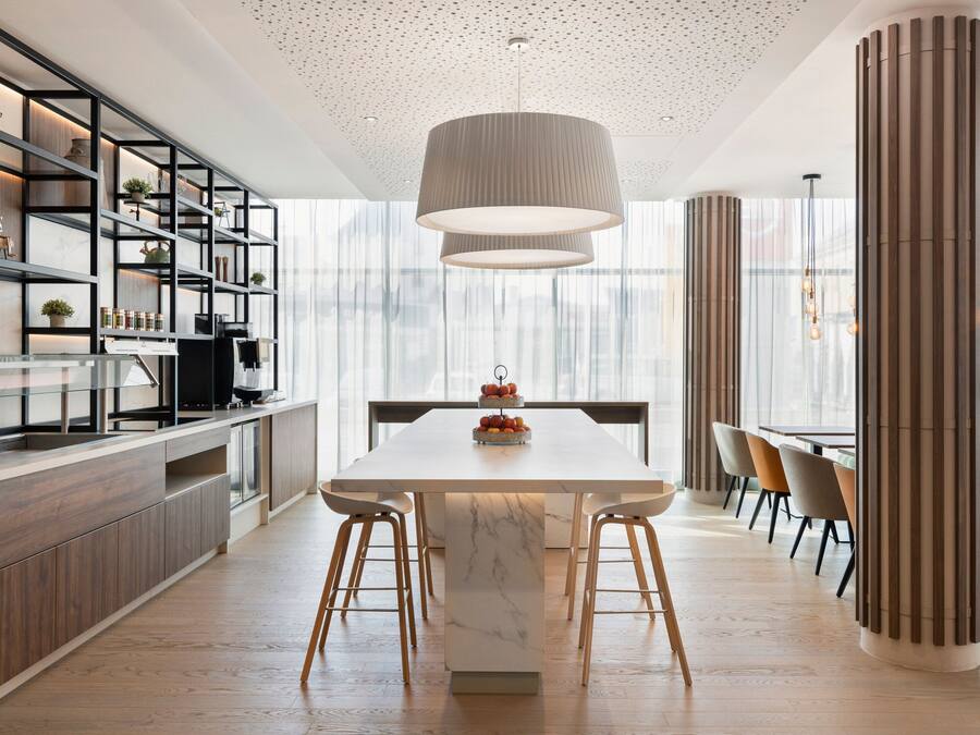 A modern kitchen with a marble island, wooden cabinets, and a large pendant light.