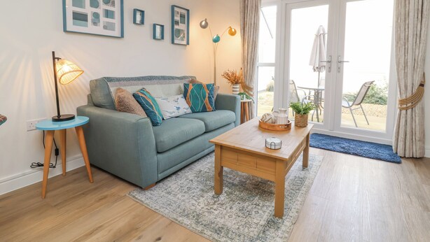 Ein modernes Wohnzimmer mit einer Couch, einem Couchtisch und Blick ins Freie.
