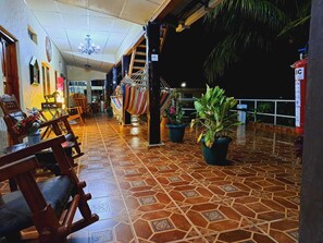 A spacious indoor area with a tiled floor, wooden chairs, potted plants, and a staircase leading to an upper level.
