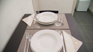 Een keurig gedekte eettafel met witte borden, bestek en gevouwen servetten.
