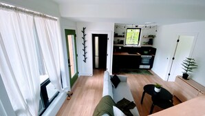 Una sala de estar moderna con un sofá, una mesa de comedor y una zona de cocina con refrigerador y estufa.