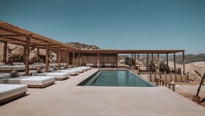 A poolside area with lounge chairs and a covered seating area, surrounded by desert landscape. - MIRA Earth Studios (Valle de Guadalupe)