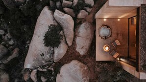 A modern outdoor seating area with a stone fire pit and a glass enclosure. - MIRA Earth Studios (Valle de Guadalupe)
