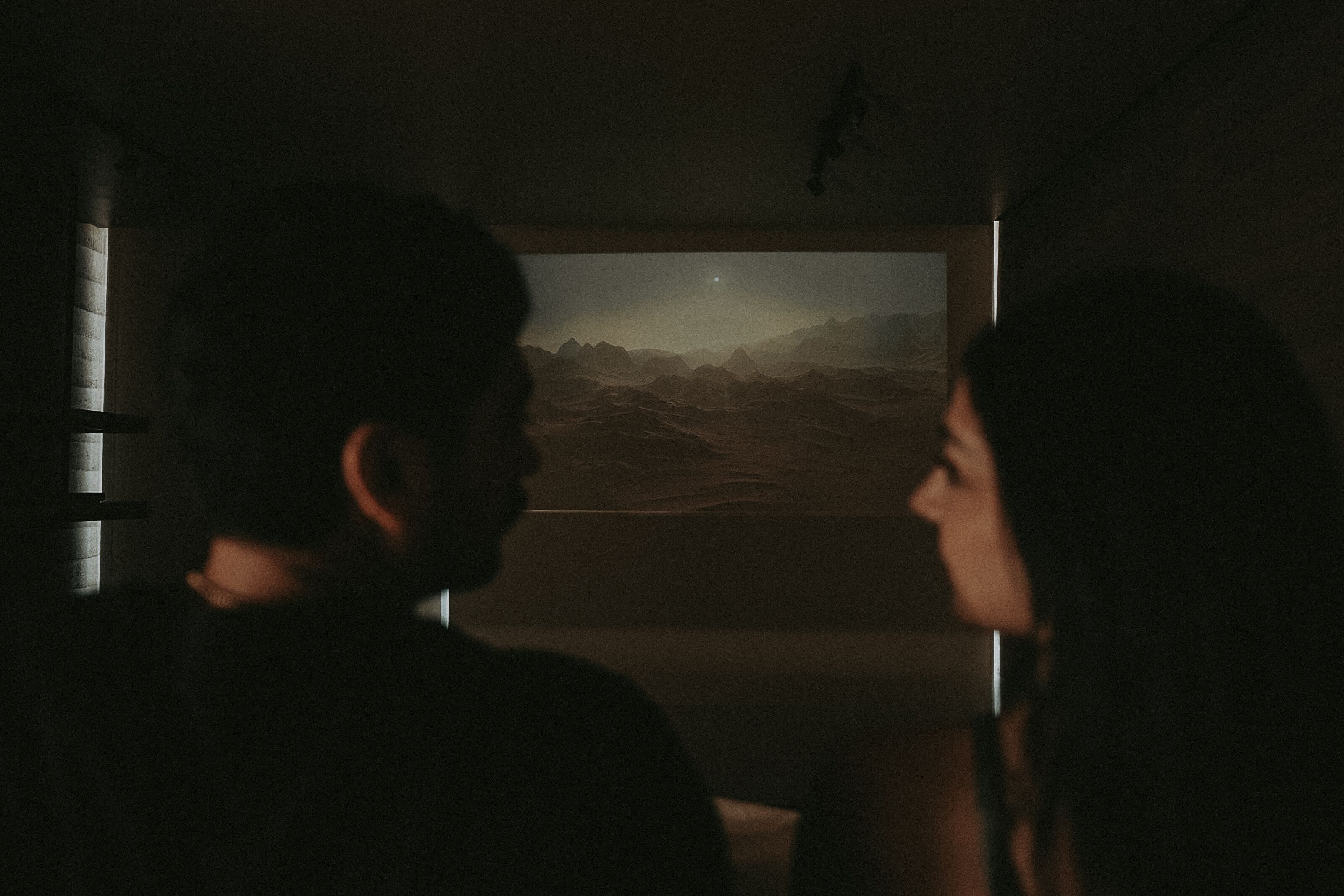 A dimly lit room with a large window displaying a mountainous landscape.