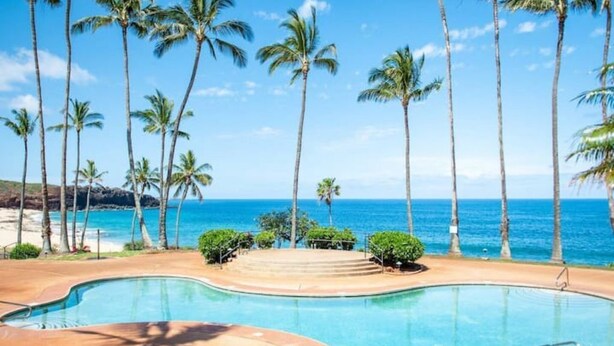A pool with a view of the ocean and palm trees. - 1-bedroom condo in Maunaloa, just 10 minutes from the beach (Maunaloa)