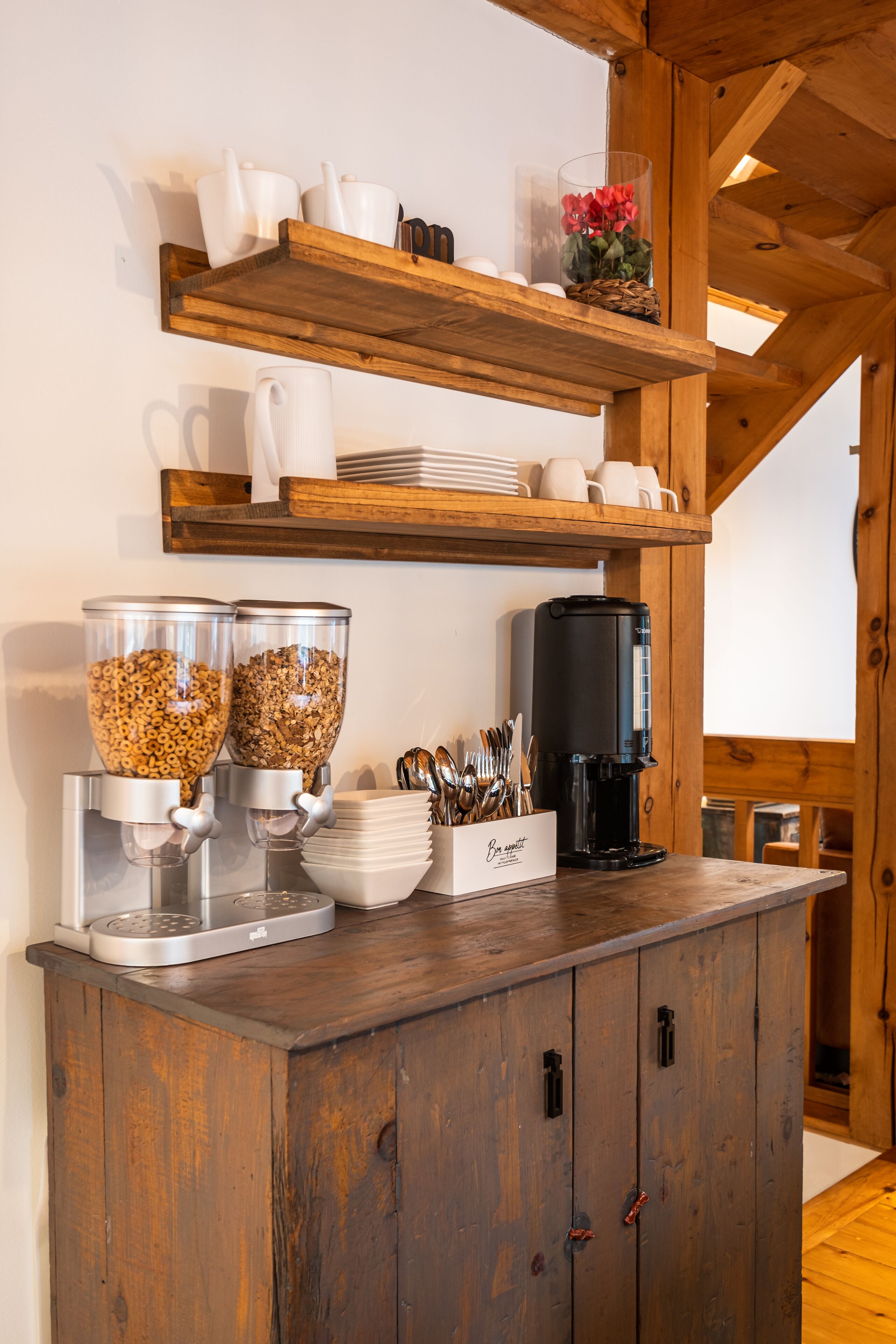 Una barra de desayuno con dispensadores de cereales, una cafetera y un cartel que dice 'Bon appétit'.