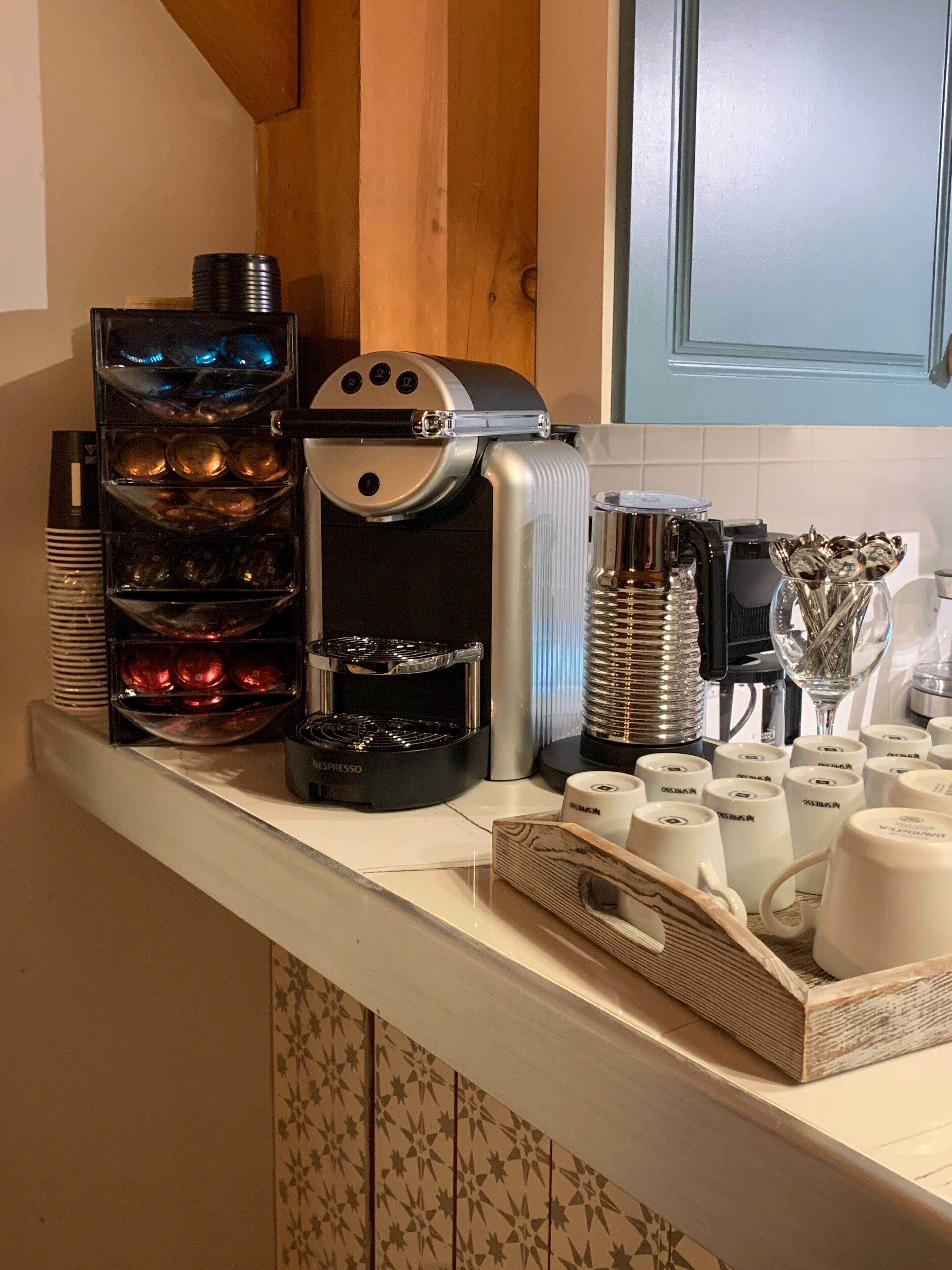 A coffee station with multiple coffee makers and a variety of coffee cups and mugs.