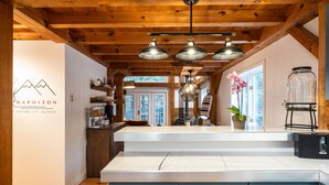 A kitchen with wooden beams, a white island, and pendant lights. - Maison Napoleon (Mont-Tremblant)