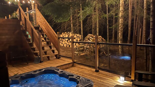 A wooden deck with a hot tub, wooden stairs, and a railing. - Maison Napoleon (Mont-Tremblant)