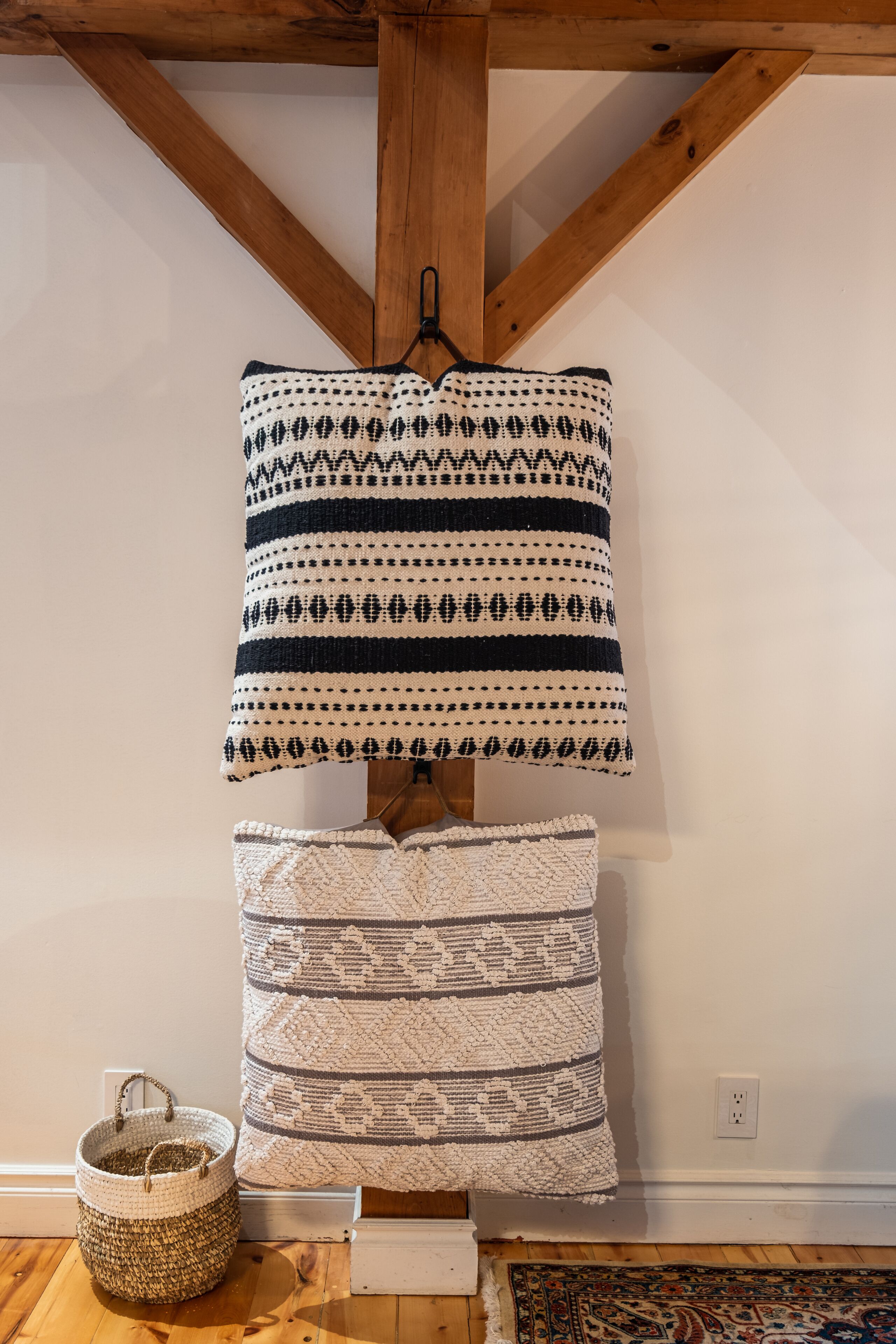 Een kamer met een houten plafond, een witte wand en een decoratief kussen aan de muur.