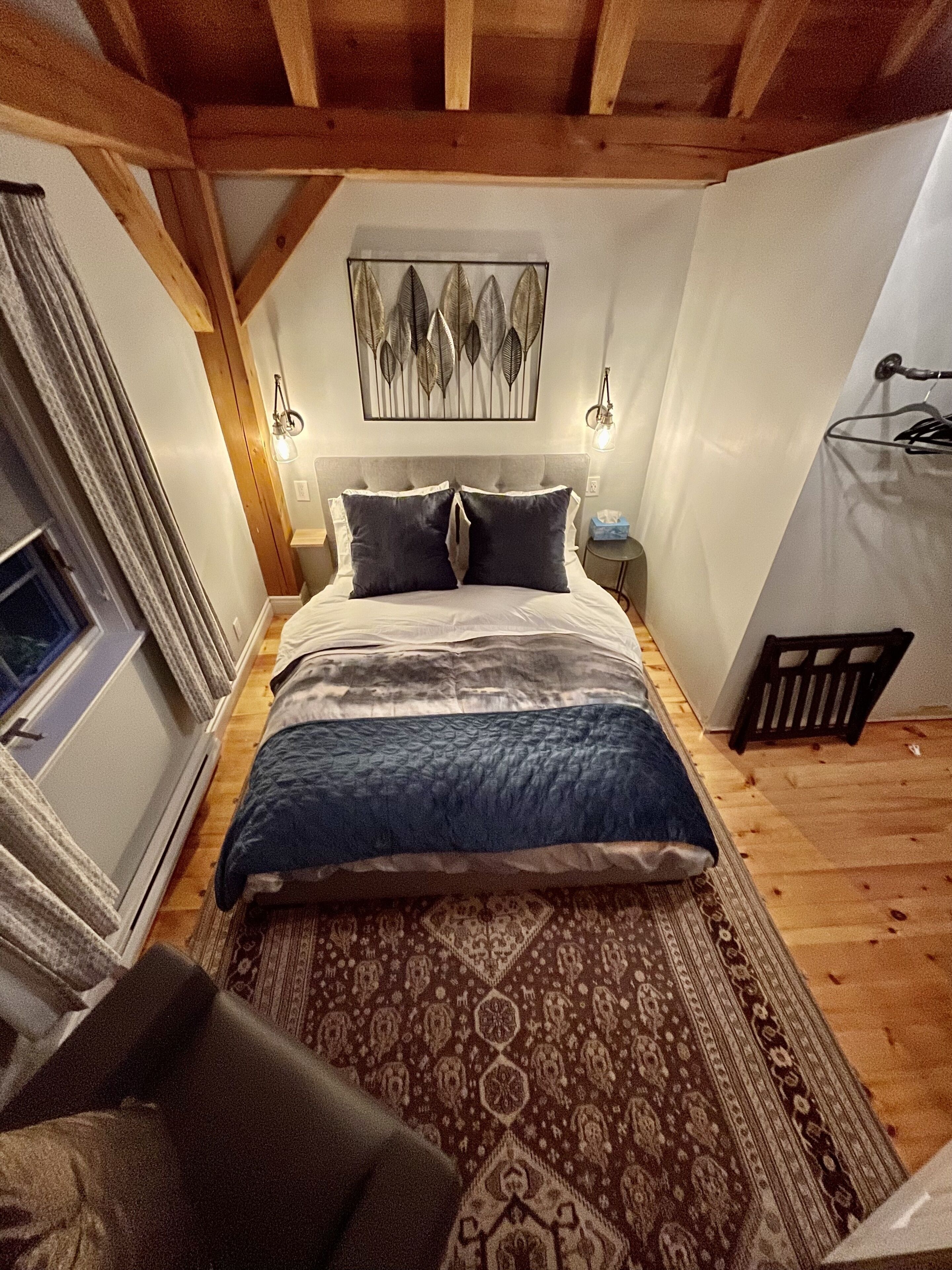 Un dormitorio con cama, mesita de noche, lámpara, ventana y puerta.