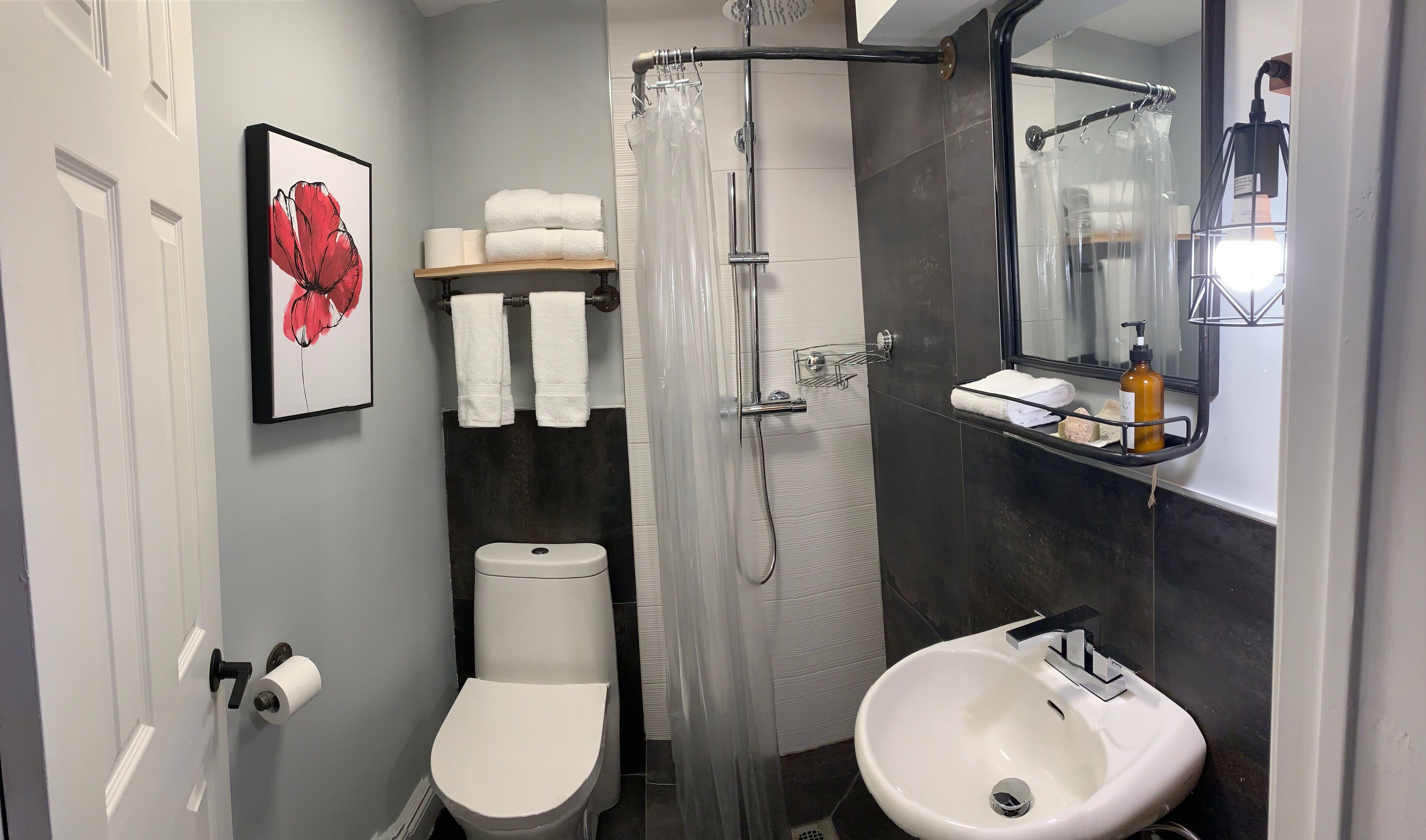 Een badkamer met toilet, douche, wastafel en spiegel.