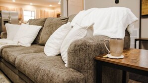 A cozy living room with a sectional sofa, a coffee table, and a door leading to another room.