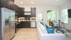 Una cocina moderna con armarios oscuros, electrodomésticos de acero inoxidable y un amplio ventanal que proporciona luz natural.