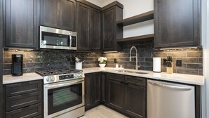 Una cocina moderna con armarios de madera oscura, electrodomésticos de acero inoxidable y un salpicadero de azulejos.