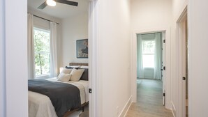 Un dormitorio con cama, ventilador de techo y ventana con cortinas.